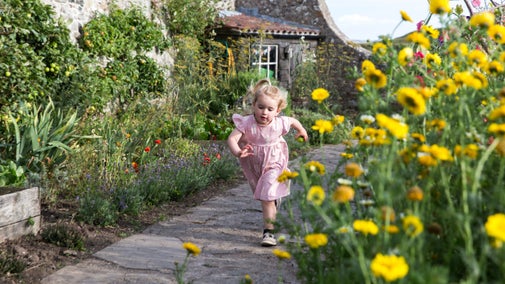 Girl running in Gertrude Jekyll's garden at Lindisfarne Castle, Northumberland
